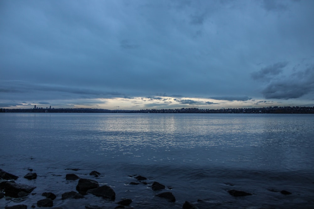 a body of water with rocks in the foreground