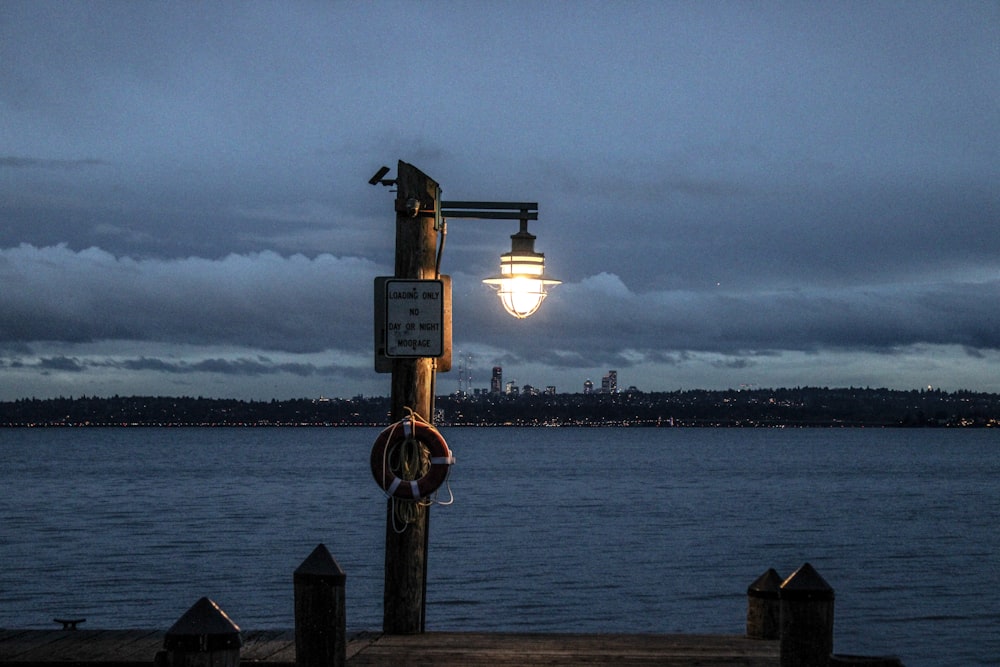 a street light sitting on the side of a body of water