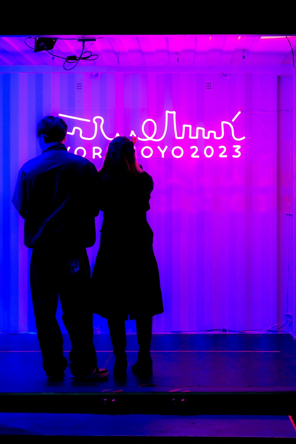 a man and a woman standing in front of a purple wall