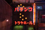 Exterior shot of the dojo at dusk, illuminated by the signature cyan neon lights against the dark matte background.
