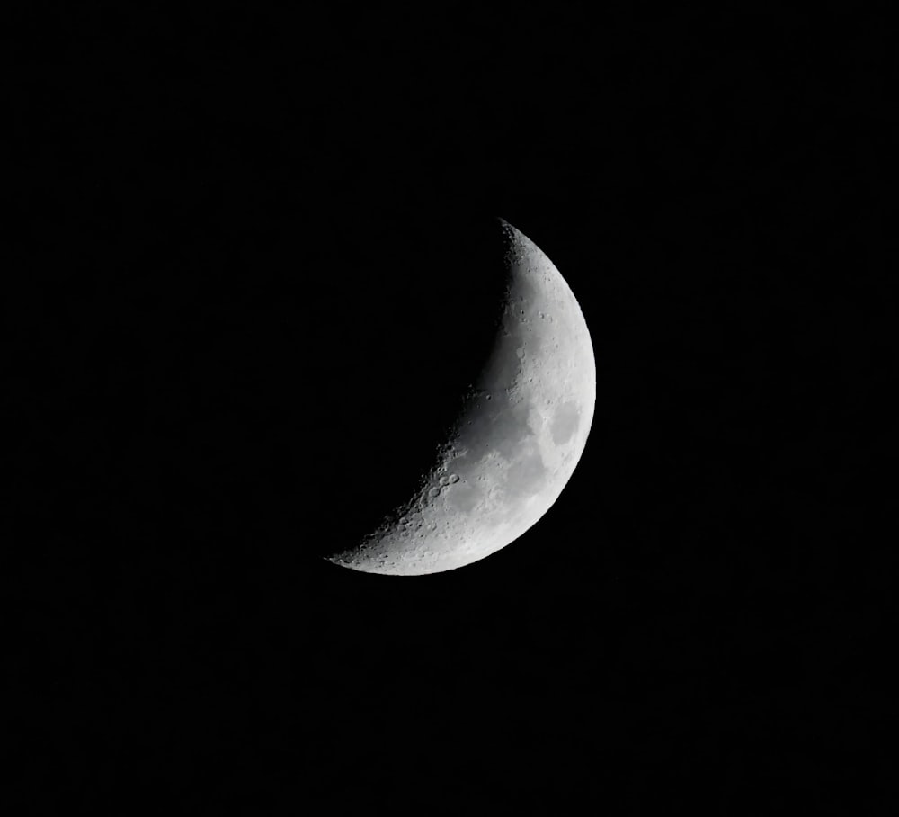 a half moon is seen in the dark sky