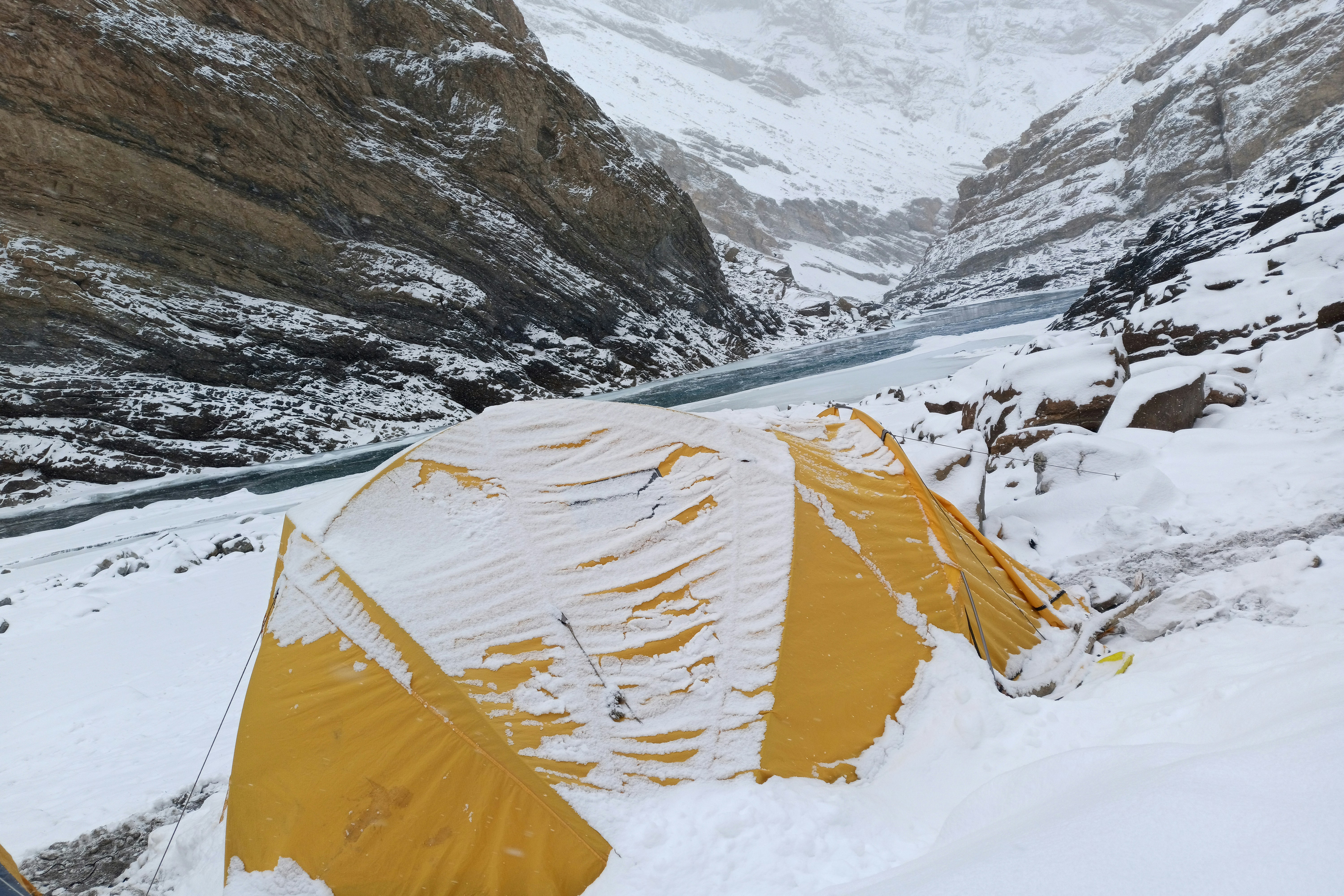 a tent pitched up in the snow near a mountain