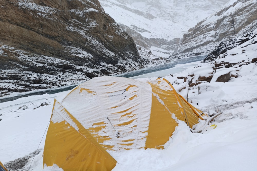 a tent pitched up in the snow near a mountain