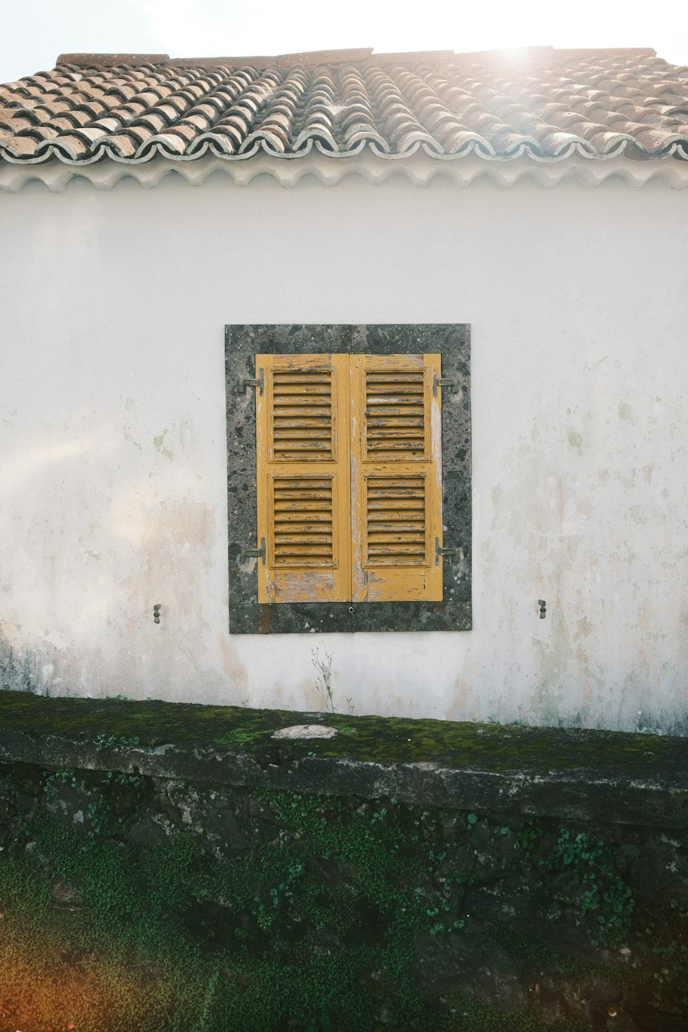 a white building with a yellow window and green grass