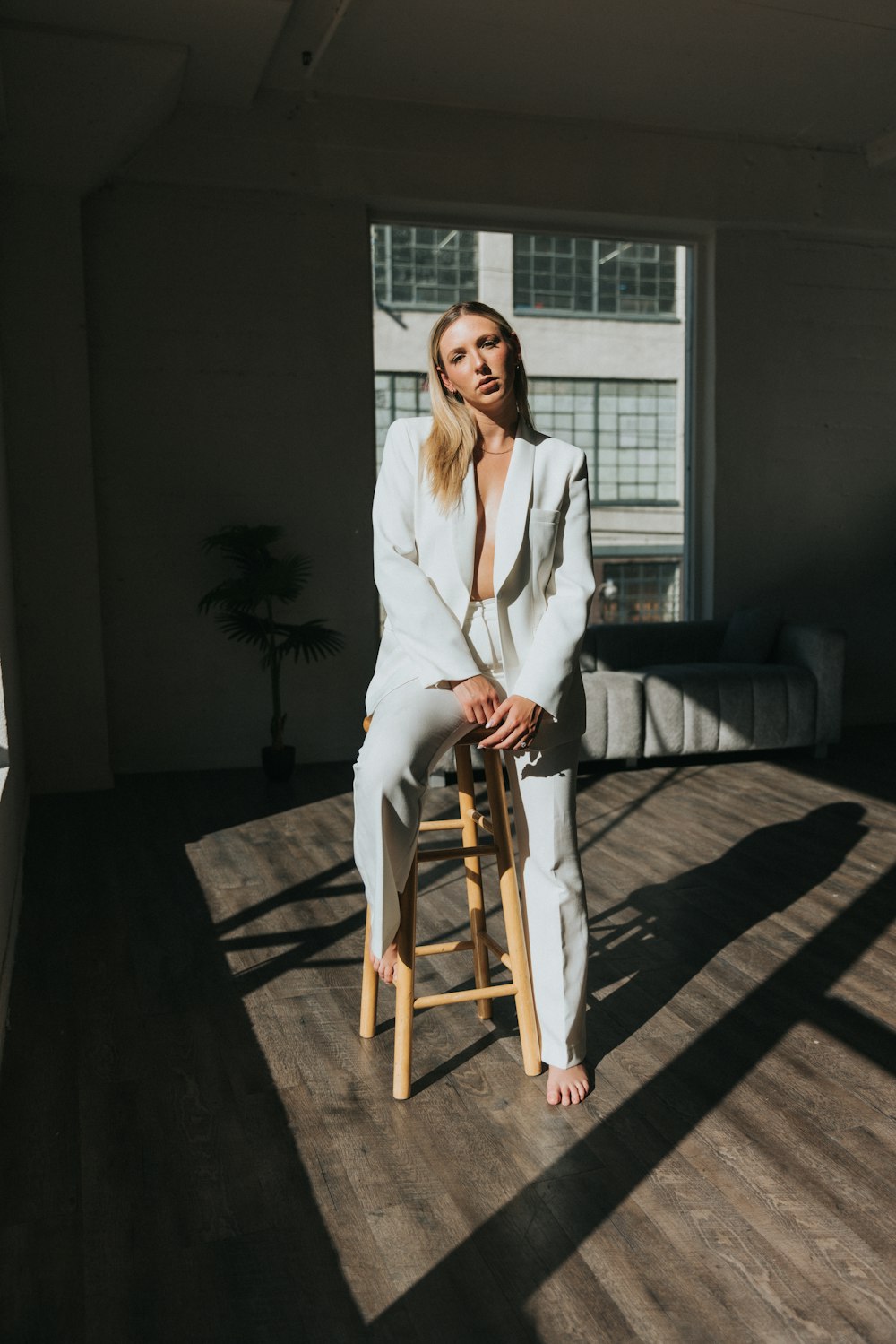 a woman in a white suit sitting on a stool