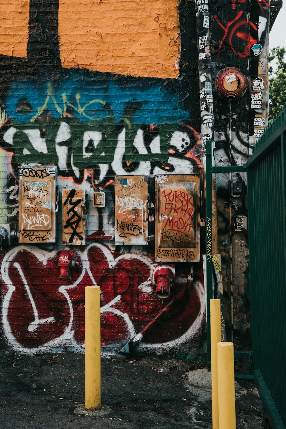 a wall covered in graffiti next to a fence