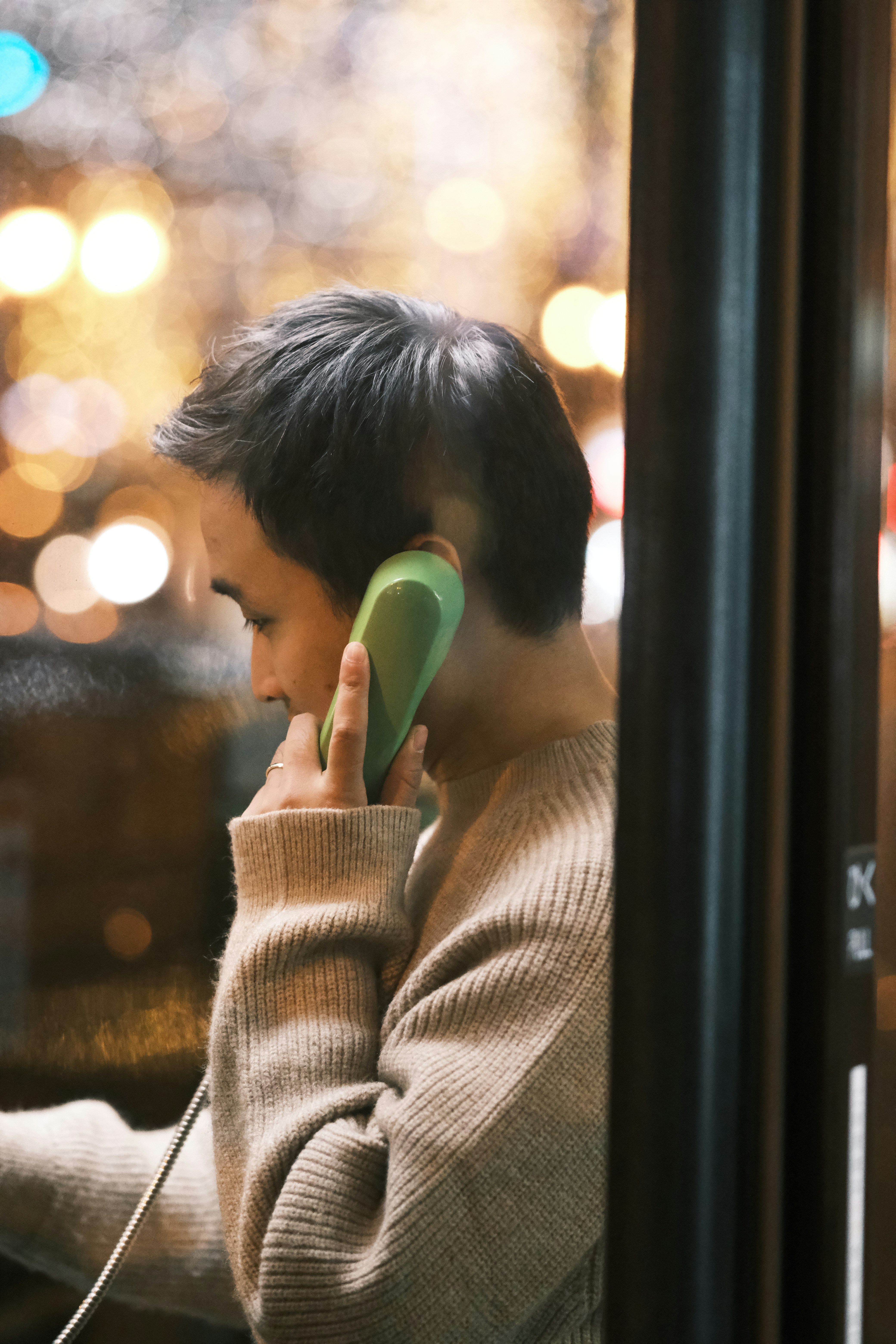 a young man talking on a green phone