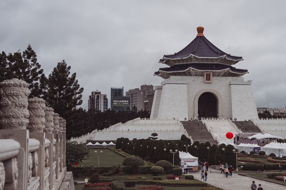 a white building with a black roof and a red ball in front of it