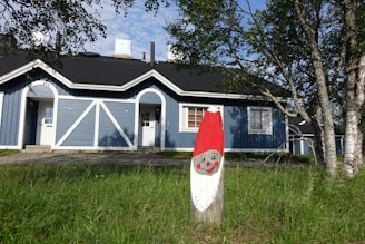 A cheerful painter applying a fresh coat of bright blue paint to a cozy house exterior on a sunny day.