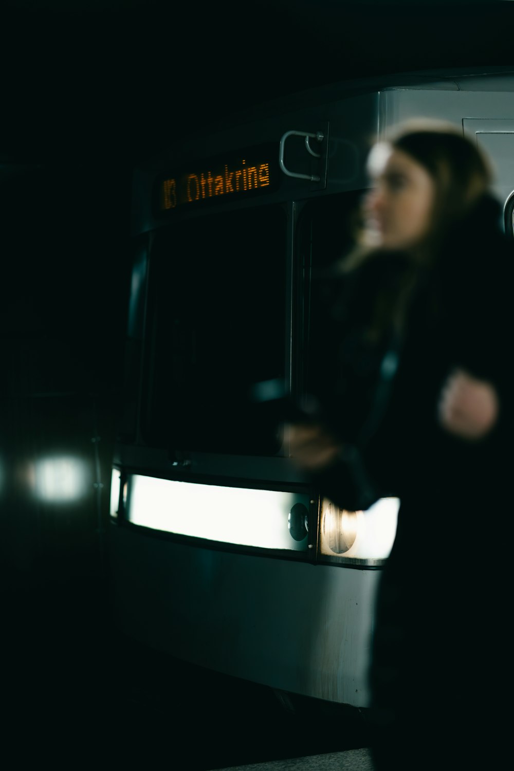 Una mujer parada frente a un autobús por la noche