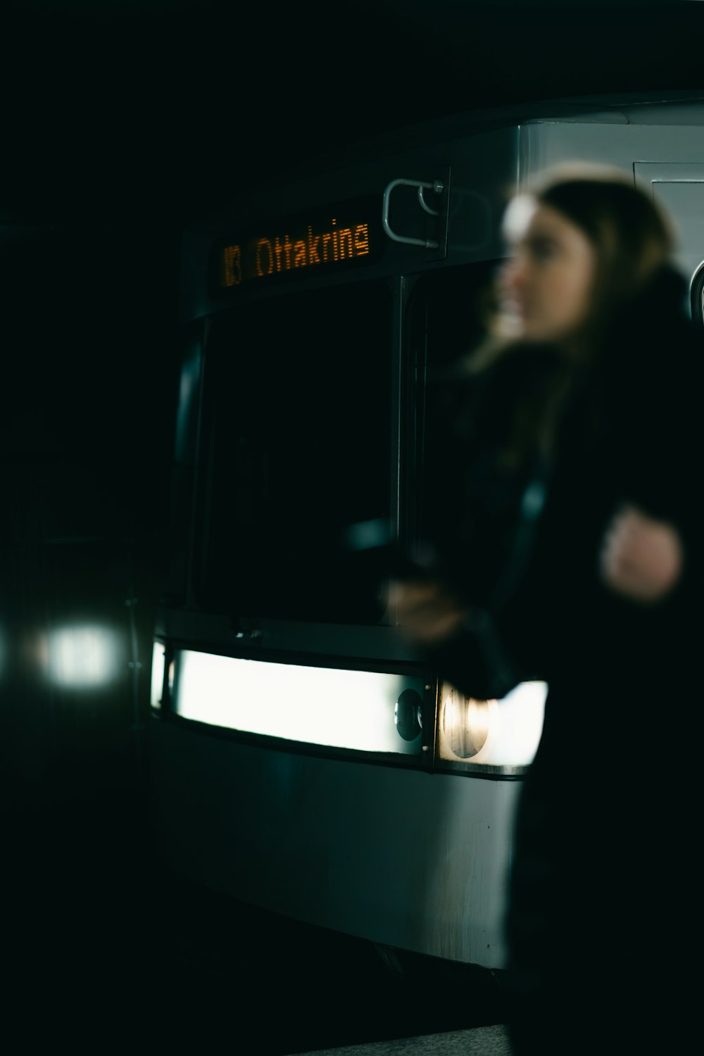 a woman standing in front of a bus at night