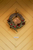 An elegant door decor piece showcasing a welcoming wreath made of intertwined branches and flowers.
