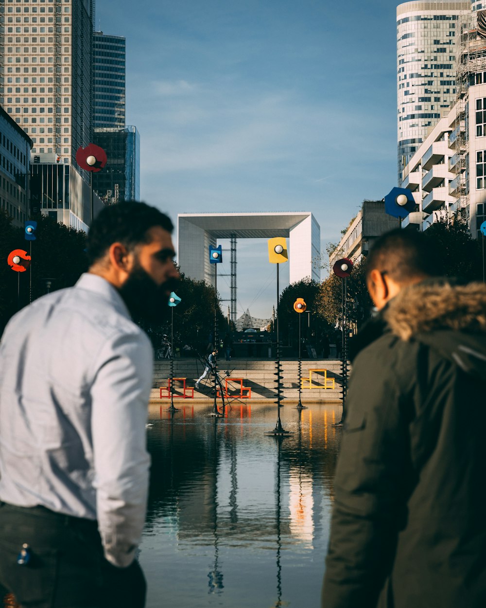 a couple of men standing next to each other near a body of water