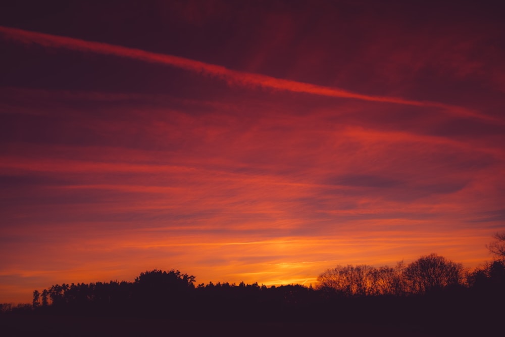 a red sky with some clouds and trees