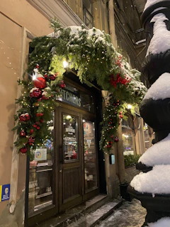 Close-up of a storefront entrance adorned with seasonal decorations and welcoming signage