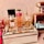 A collection of various perfume bottles arranged on a mirrored tray with decorative crystal embellishments. The bottles are of different sizes and designs, including recognizable brands with elegant labeling. The setting exudes a luxurious and sophisticated ambiance.