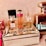 A collection of various perfume bottles arranged on a mirrored tray with decorative crystal embellishments. The bottles are of different sizes and designs, including recognizable brands with elegant labeling. The setting exudes a luxurious and sophisticated ambiance.