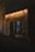 A dimly lit storefront with a rustic appearance is adorned with string lights. The sign above the door displays the word 'Trouvailles'. The cobblestone street leading to the entrance adds an old-world charm.