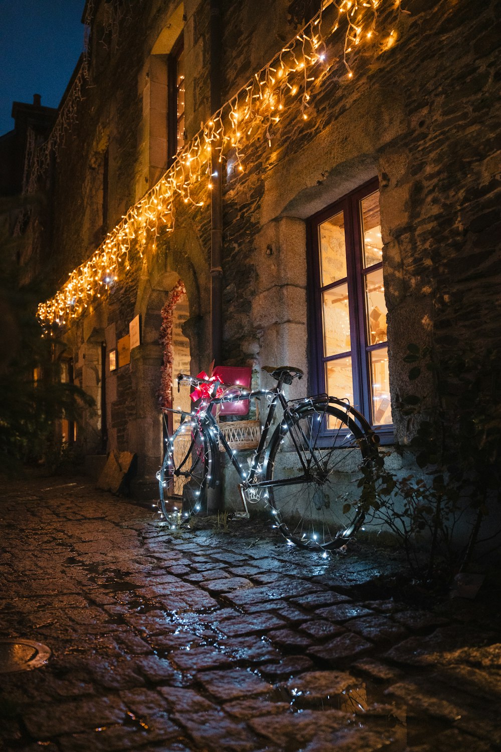 a bicycle parked in front of a building covered in christmas lights