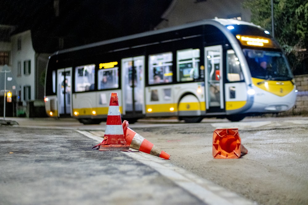 um ônibus dirigindo por uma rua ao lado de cones de trânsito