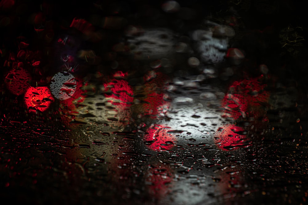 a close up of a rain covered window with red lights