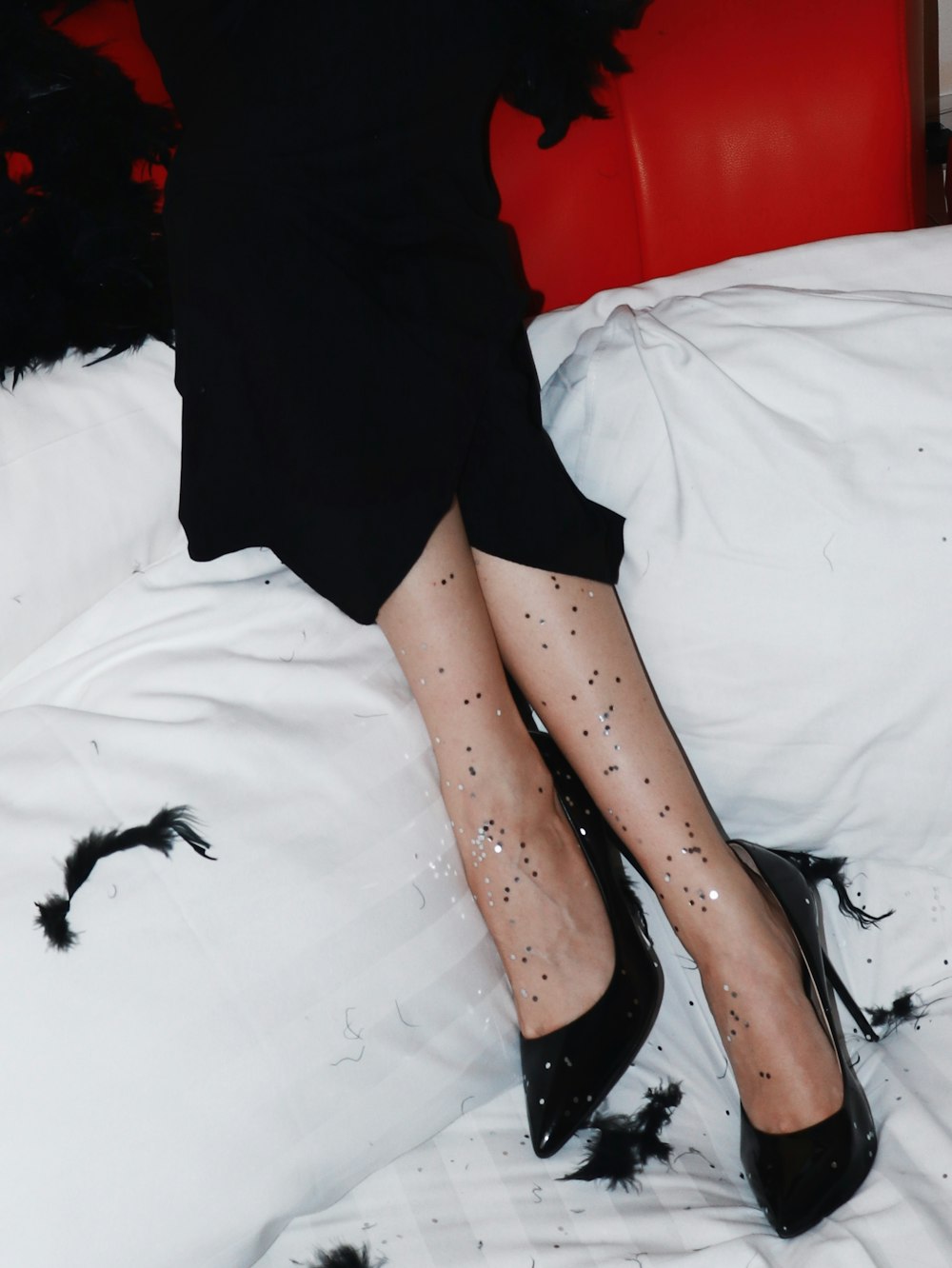 a woman in black shoes and black stockings sitting on a bed