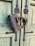 A large, intricately designed padlock with a dragon motif is fastened to a wooden door with a faded green paint finish. The door features black ornamental metalwork with a floral pattern around the lock area.