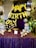 A decorative setup featuring gold balloon letters spelling out 'Happy Birthday' is prominently displayed. The background is adorned with a rich purple curtain, and the table in front is covered in a sparkling purple cloth. The table holds various golden decorative items, including a candelabra and globe-shaped ornaments. Surrounding the setup are lush green plants and helium balloons in black, white, and metallic colors.