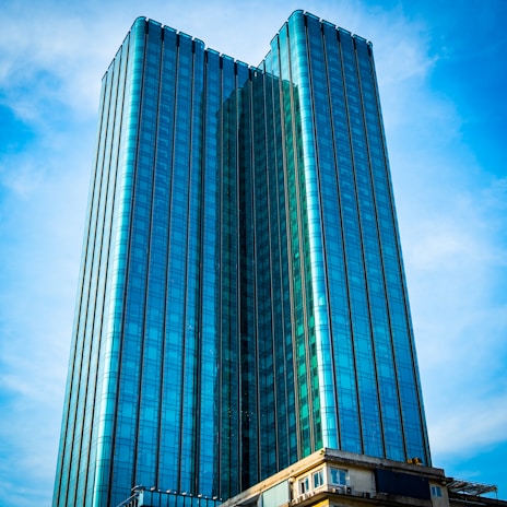 A sleek modern skyscraper representing real estate investments under a clear blue sky.