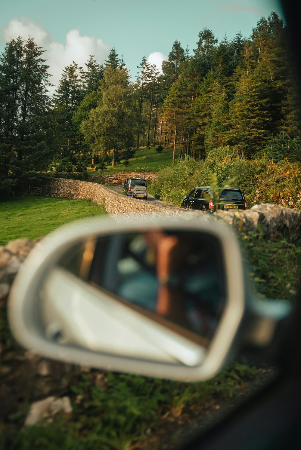 a car's side view mirror reflecting a road in the rear view mirror