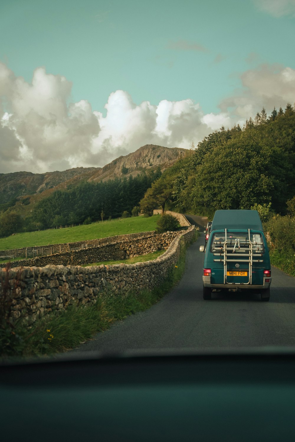 uma van dirigindo por uma estrada ao lado de uma colina verde exuberante