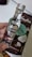 A small bottle of clear liquor labeled 'Stalinska Silver Premium Vodka' is held by a hand. Behind the bottle is a package of chocolate with coconut pieces, labeled as having 33% cacao and featuring coconut imagery.