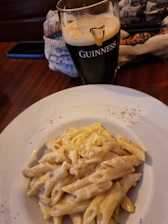 Close-up of a frothy Guinness pint beside a juicy gourmet burger on a rustic wooden table.