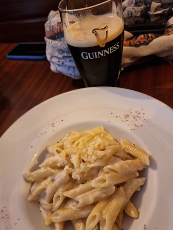 Close-up of a frothy Guinness pint beside a juicy gourmet burger on a rustic wooden table.