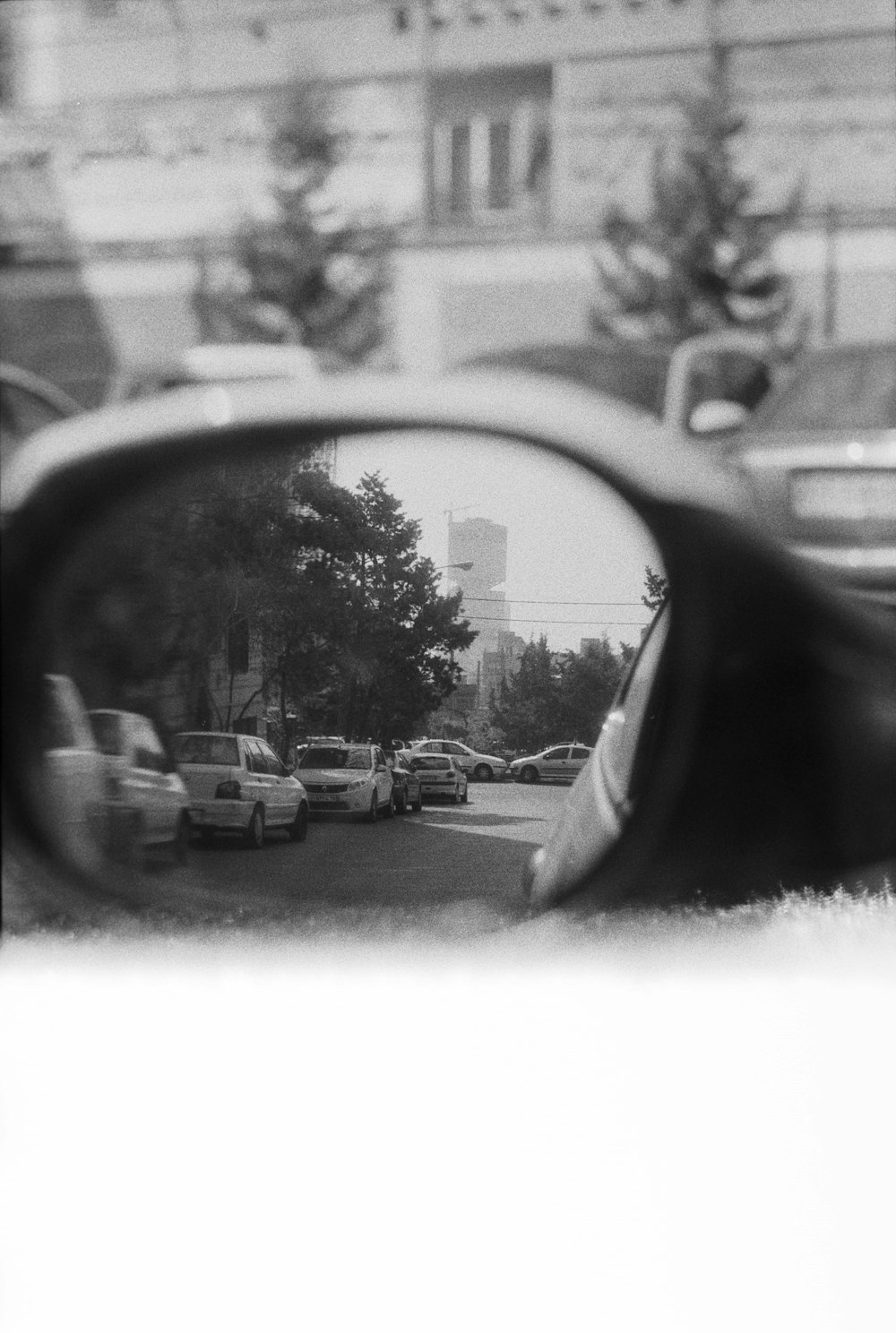 a rear view mirror reflecting cars on a city street