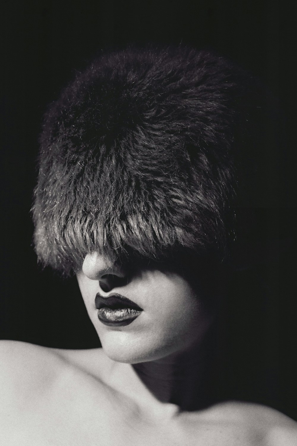a black and white photo of a woman wearing a fur hat