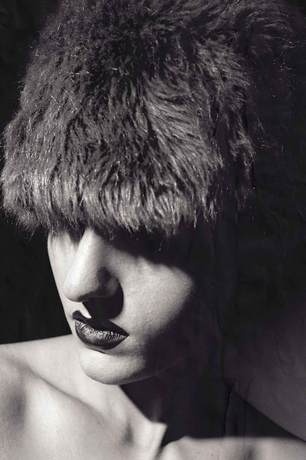 a black and white photo of a woman wearing a fur hat