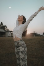 a woman standing in a field with her arms outstretched