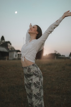 a woman standing in a field with her arms outstretched