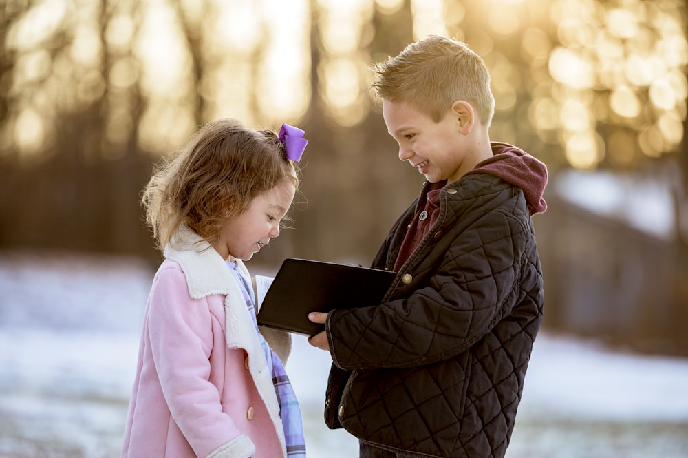 a boy and a girl standing next to each other in the snow