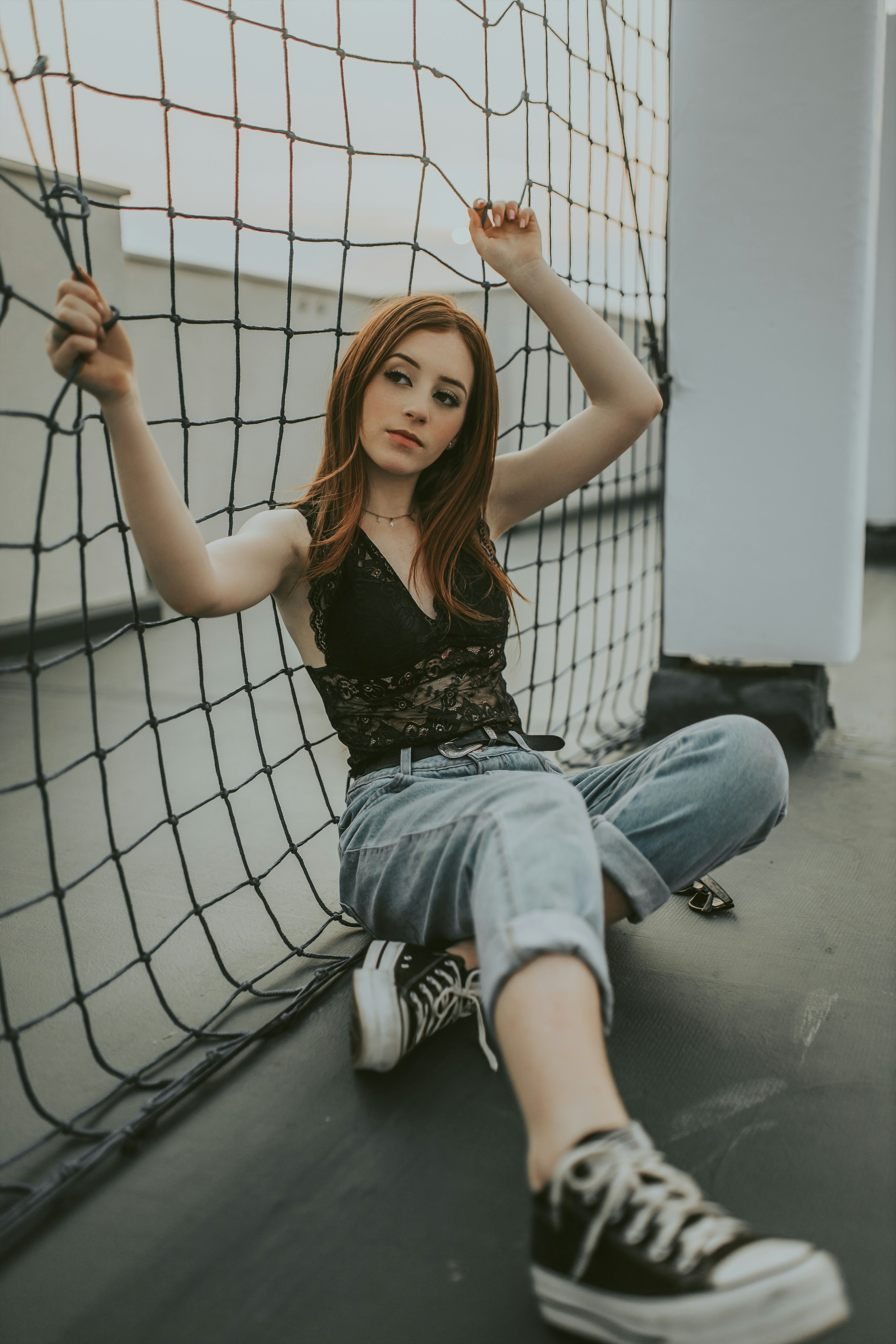 a woman sitting on the ground next to a net