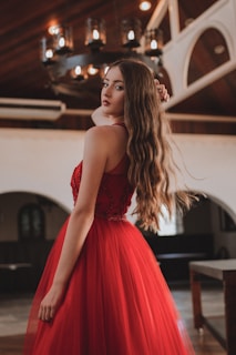 An elegant cocktail dress in rich ruby red fabric with subtle shimmer, styled with delicate jewelry