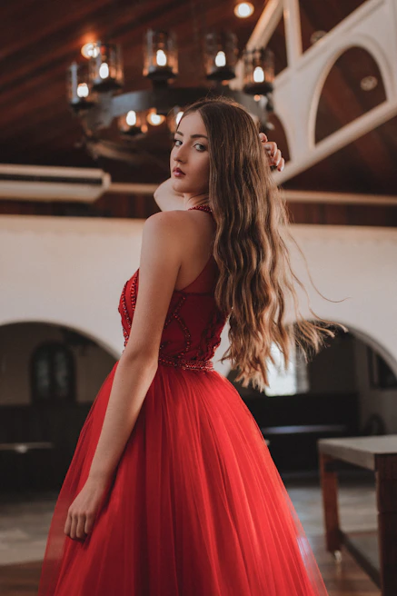 A rich wine-colored dress with delicate lace details, hanging gracefully with soft lighting highlighting its texture.