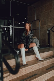 Model sitting on stairs wearing layered streetwear pieces with urban graffiti behind