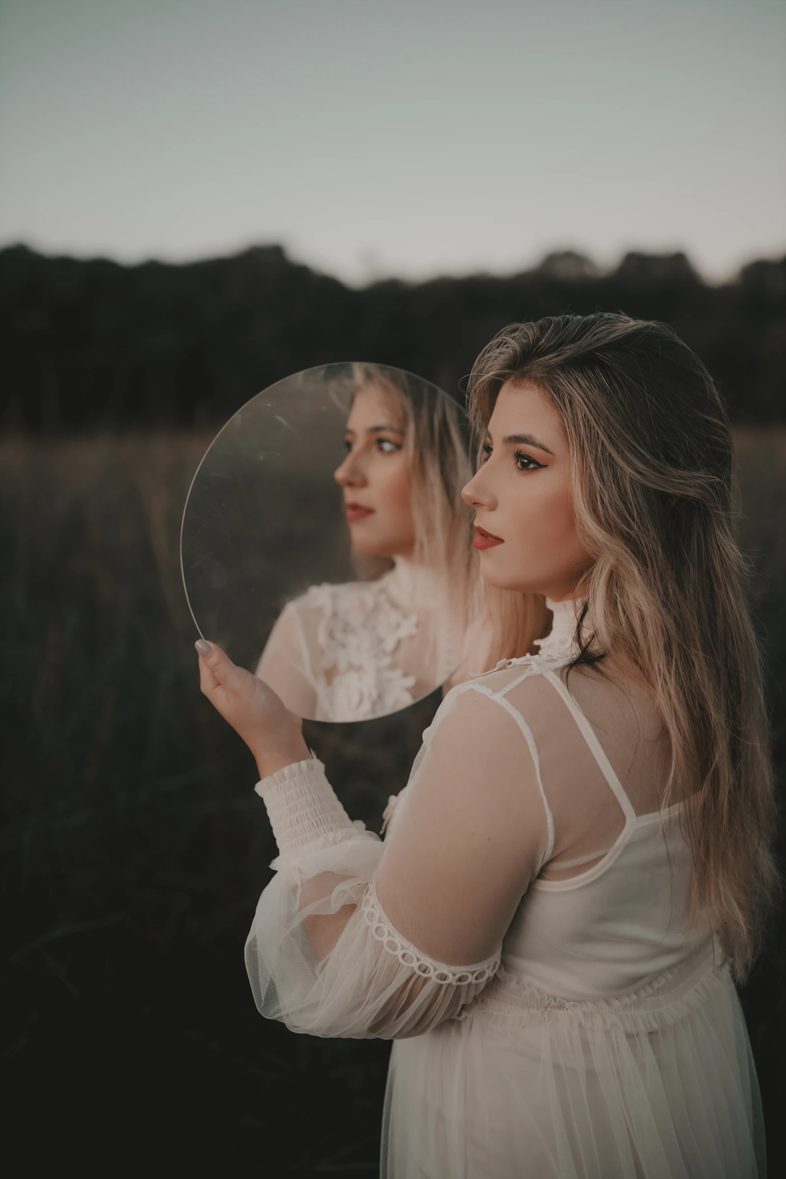 a woman in a white dress looking at herself in a mirror