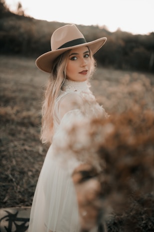 a woman wearing a hat standing in a field
