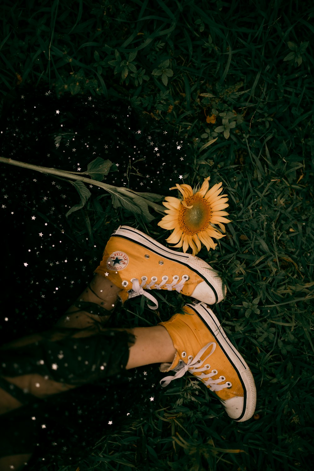 a person's feet in yellow sneakers and a sunflower