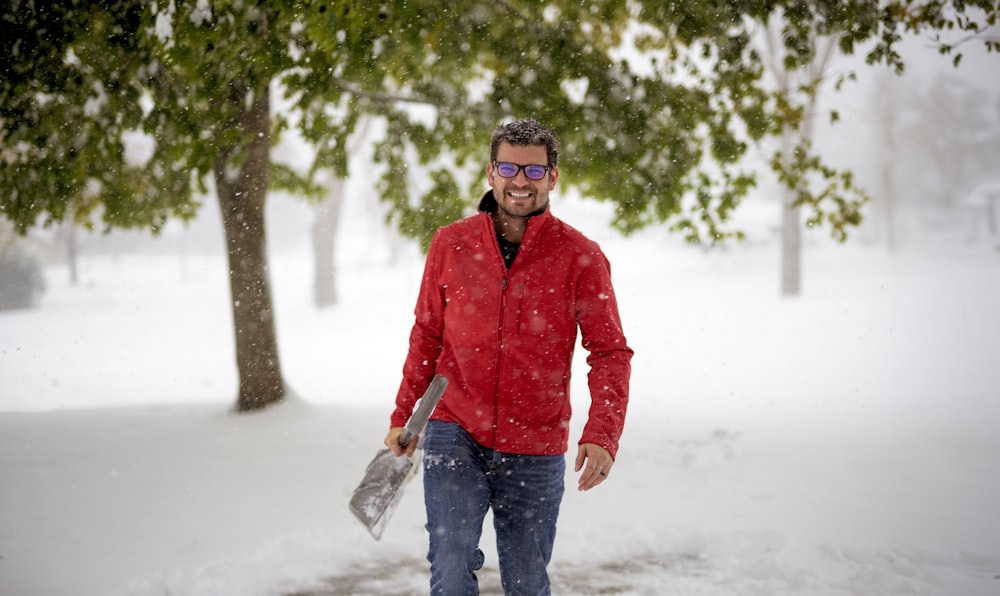 Un homme vêtu d’une veste rouge marche dans la neige