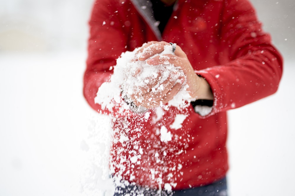 Ein Mann in einer roten Jacke wirft Schnee in die Luft