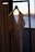 A close-up of a beautifully designed dress hanging on a wooden hanger against a soft, neutral background.